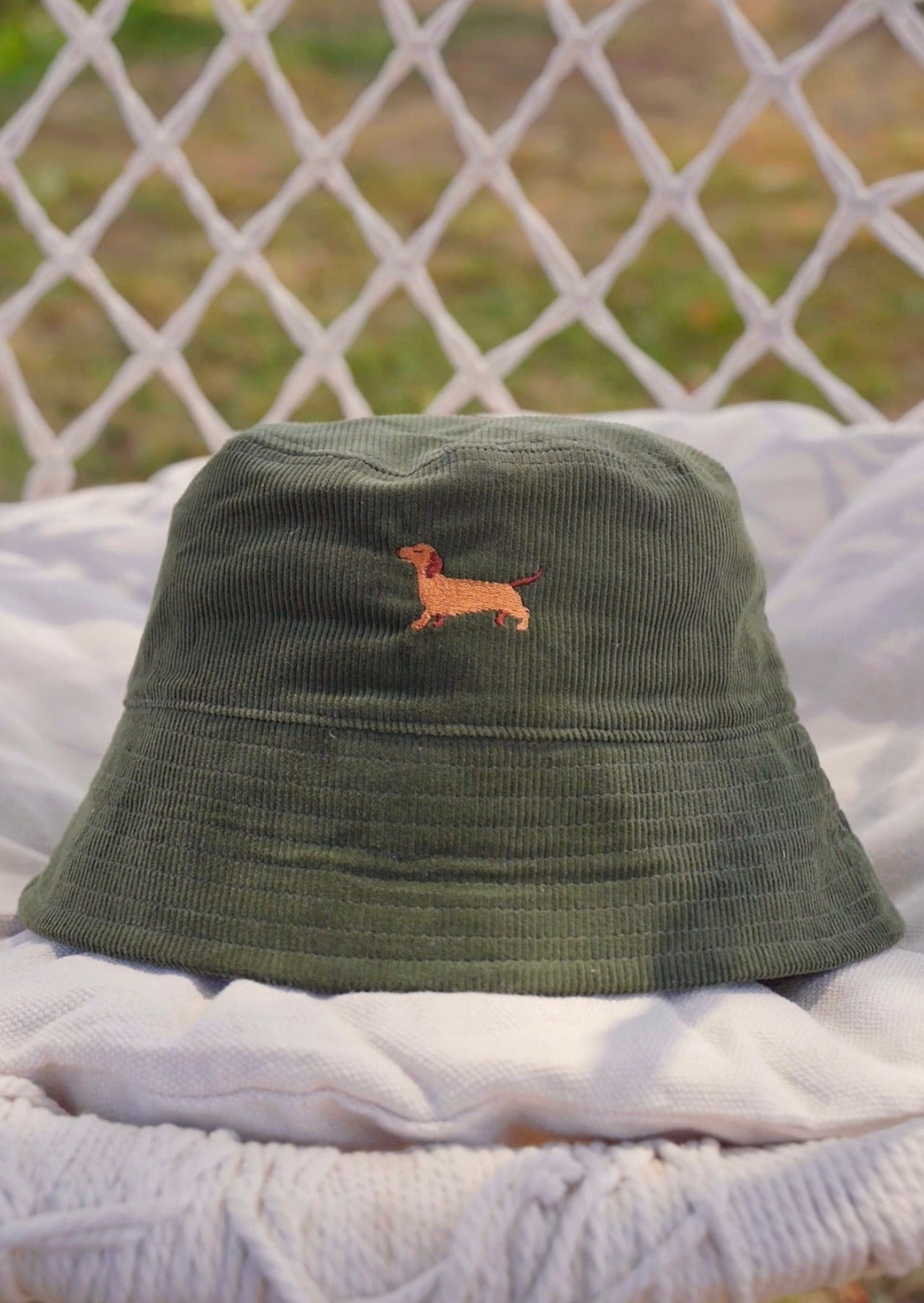 Nahaufnahme des grünen Cordhuts mit Dackel-Stickerei in natürlichem Licht